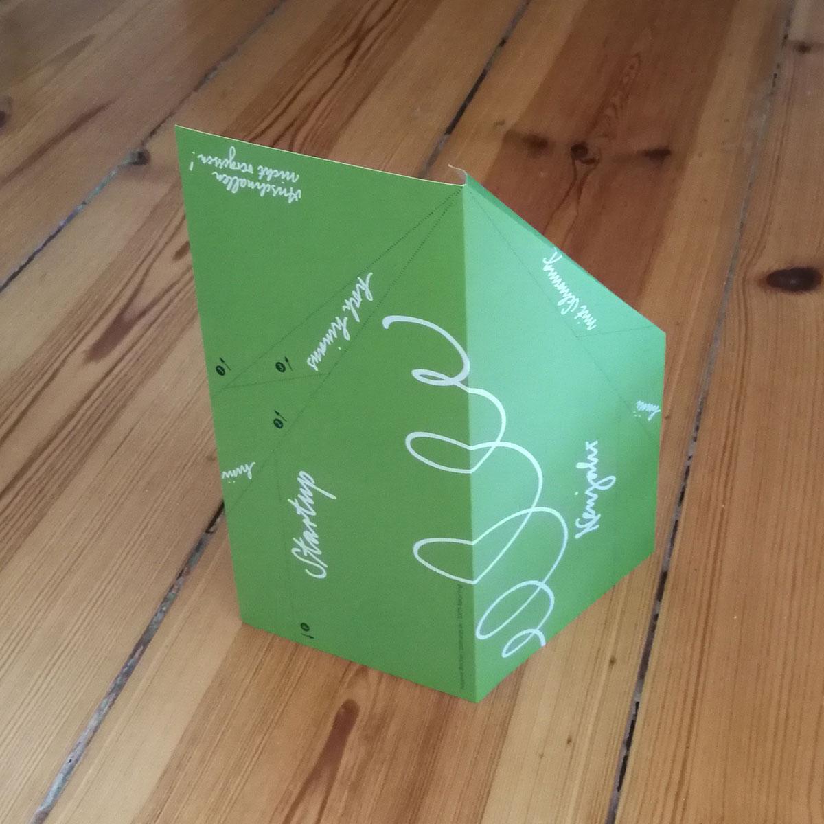 grüne Neujahrskarte zum Basteln eines Papierfliegers (mit gefalteter Ecke)